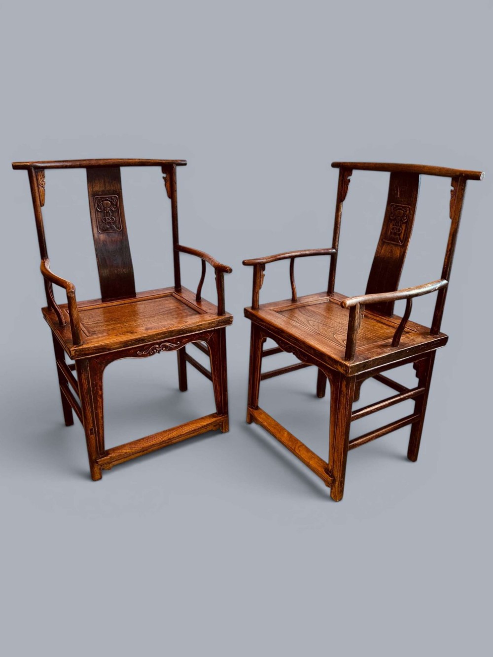 A pair of late nineteenth-century Chinese dark elm armchairs featuring carved central back splats and curved crest rails.