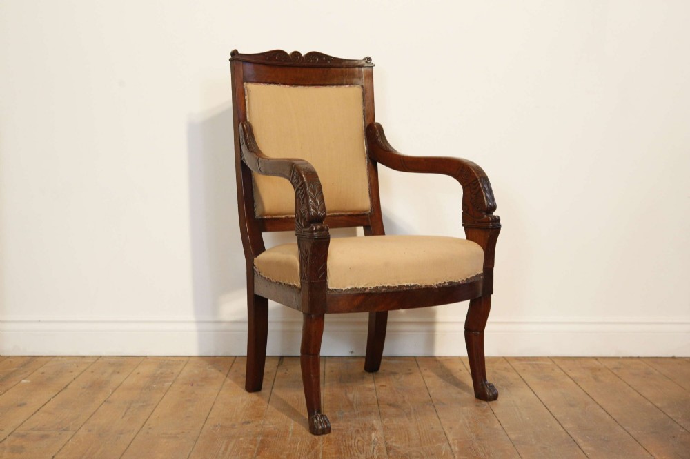 An early nineteenth-century French Empire carved mahogany armchair with padded seat and backrest, curved arms, and carved front legs. View II
