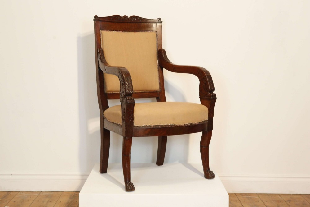 An early nineteenth-century French Empire carved mahogany armchair with padded seat and backrest, curved arms, and carved front legs. View III