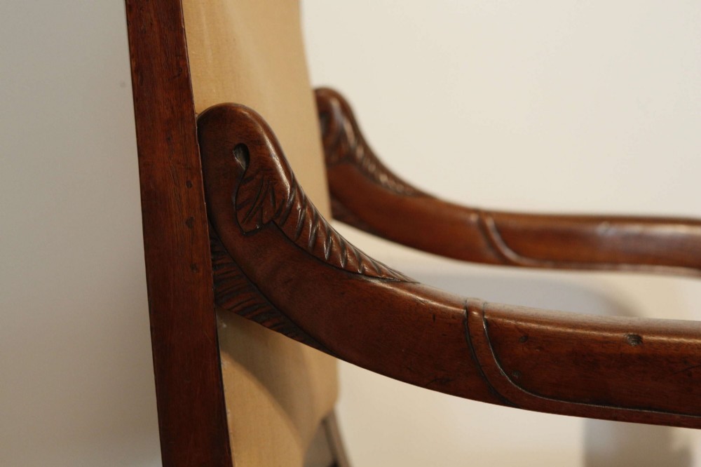 An early nineteenth-century French Empire carved mahogany armchair with padded seat and backrest, curved arms, and carved front legs. View VII
