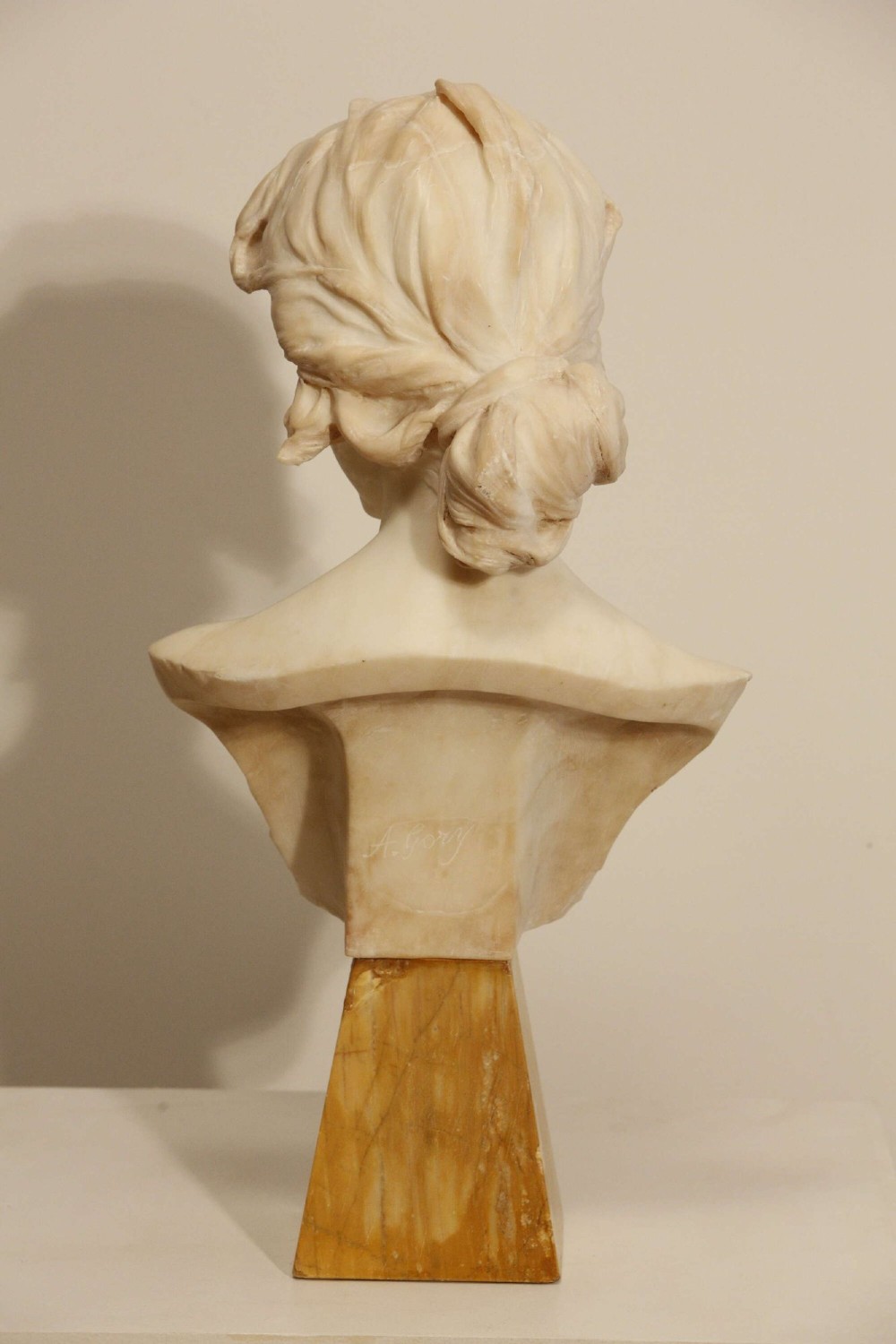 An early twentieth-century carved Carrara marble bust depicting a young female subject with a carved floral corsage, mounted on a wooden pedestal base. View VIII
