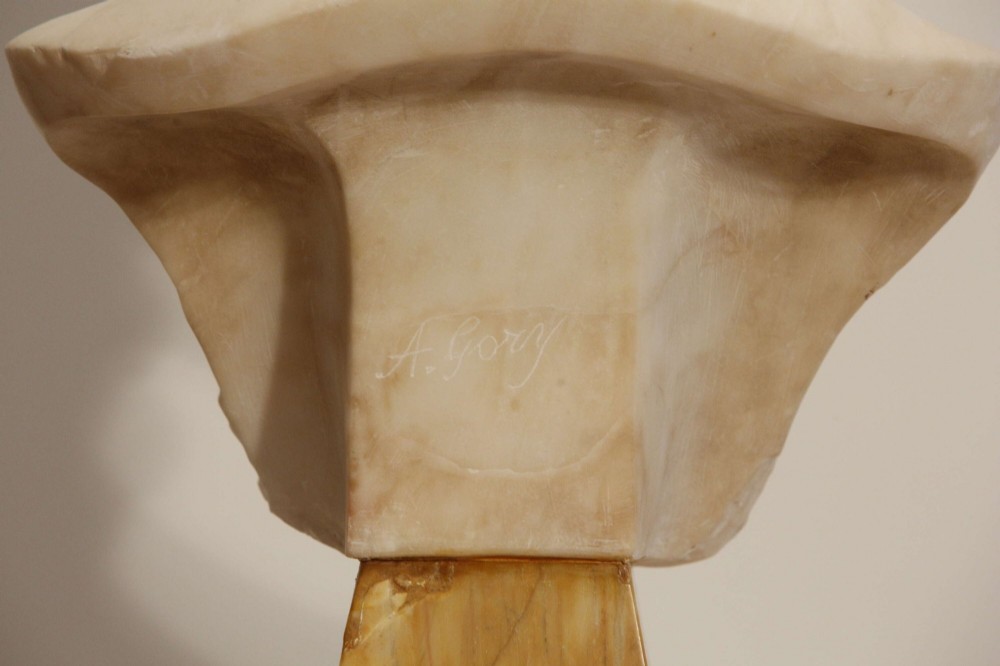 An early twentieth-century carved Carrara marble bust depicting a young female subject with a carved floral corsage, mounted on a wooden pedestal base. View IX