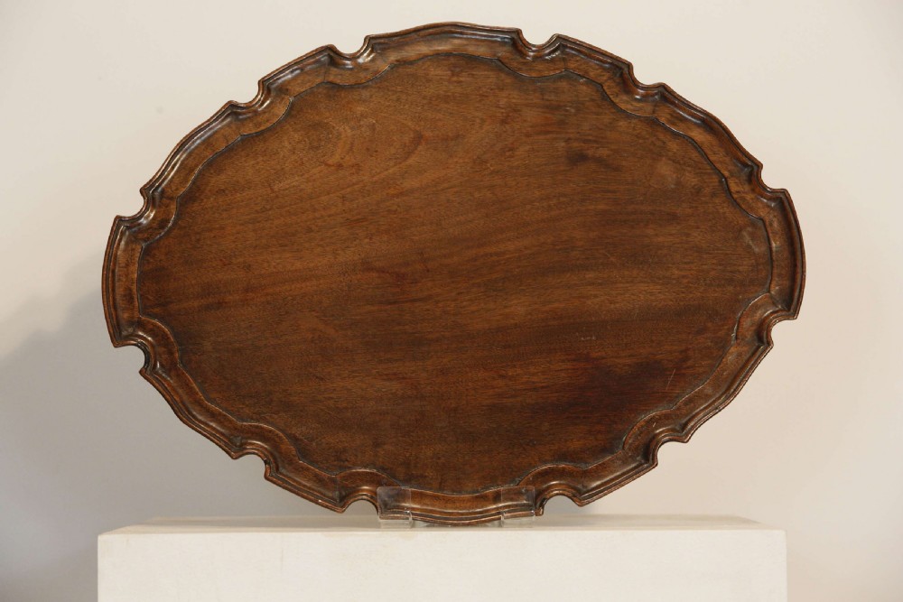 A George III mahogany oval tray featuring a hand-carved pie crust scalloped rim and rich wood grain. View IV