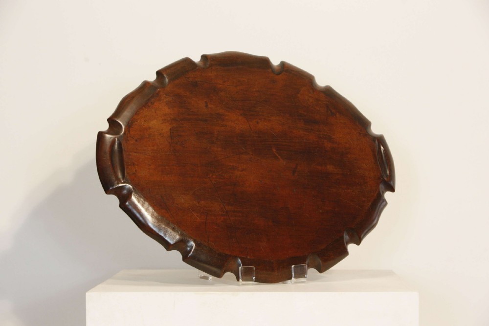 A George III mahogany oval tray featuring a hand-carved pie crust scalloped rim and rich wood grain. View IX