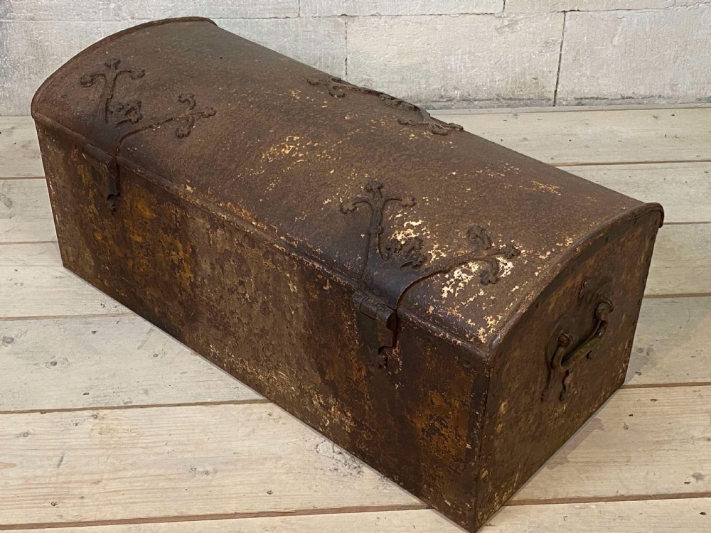 An 18th-century wrought iron trunk featuring a domed lid, decorative latch detail, side drop handles, and an oxidised rust brown surface. View IX