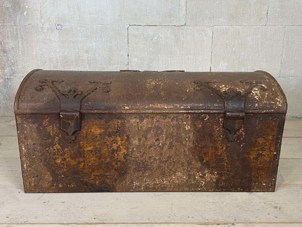 An 18th-century wrought iron trunk featuring a domed lid, decorative latch detail, side drop handles, and an oxidised rust brown surface. View X