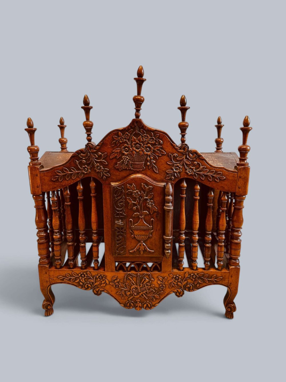 A carved walnut French panetiere bread cupboard featuring turned balusters, floral carvings, turned finials, and a central cabinet door with an iron lock plate.