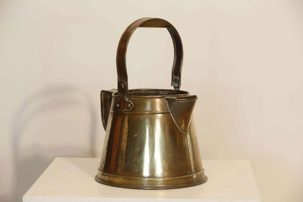 An antique brass hot water can featuring a tapered cylindrical body, broad overhead swinging handle, rear side handle, and riveted construction. View III