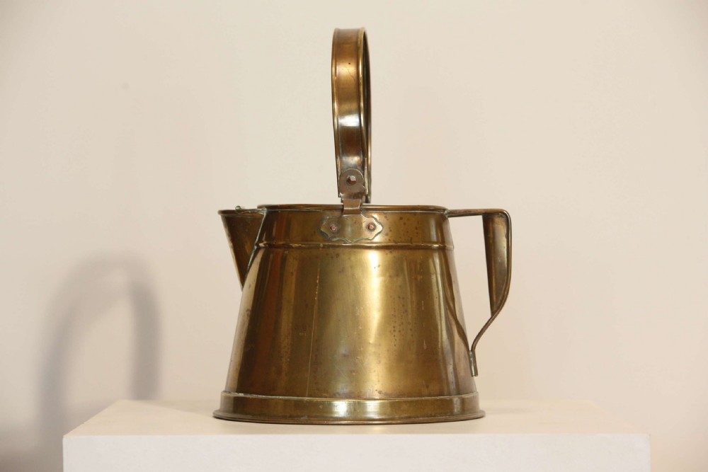 An antique brass hot water can featuring a tapered cylindrical body, broad overhead swinging handle, rear side handle, and riveted construction. View IV