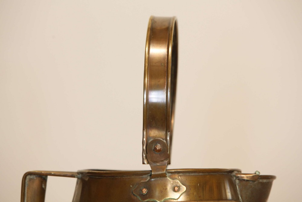 An antique brass hot water can featuring a tapered cylindrical body, broad overhead swinging handle, rear side handle, and riveted construction. View VIII