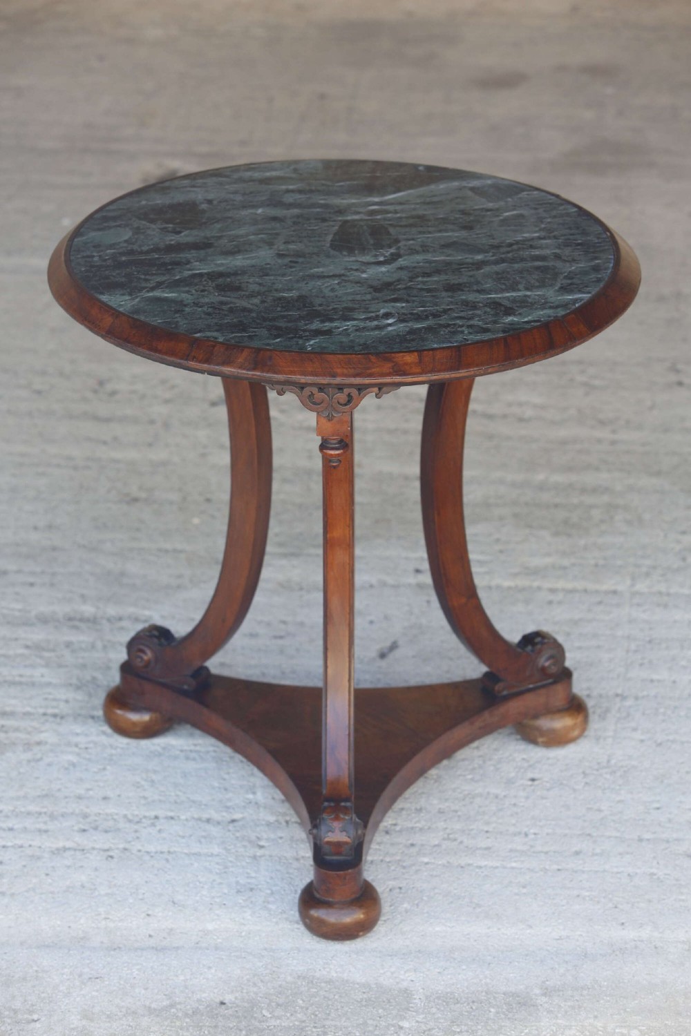 A circular 19th-century French gueridon table featuring a dark green marble top supported by three curved mahogany legs resting on a shaped triform base. View II