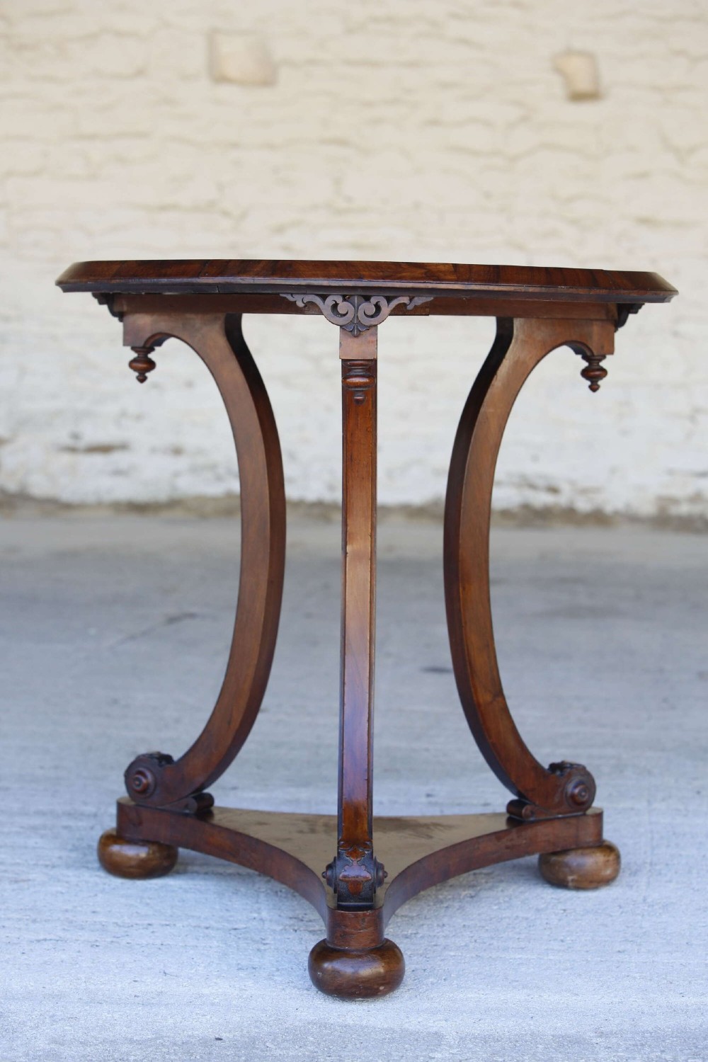 A circular 19th-century French gueridon table featuring a dark green marble top supported by three curved mahogany legs resting on a shaped triform base. View III