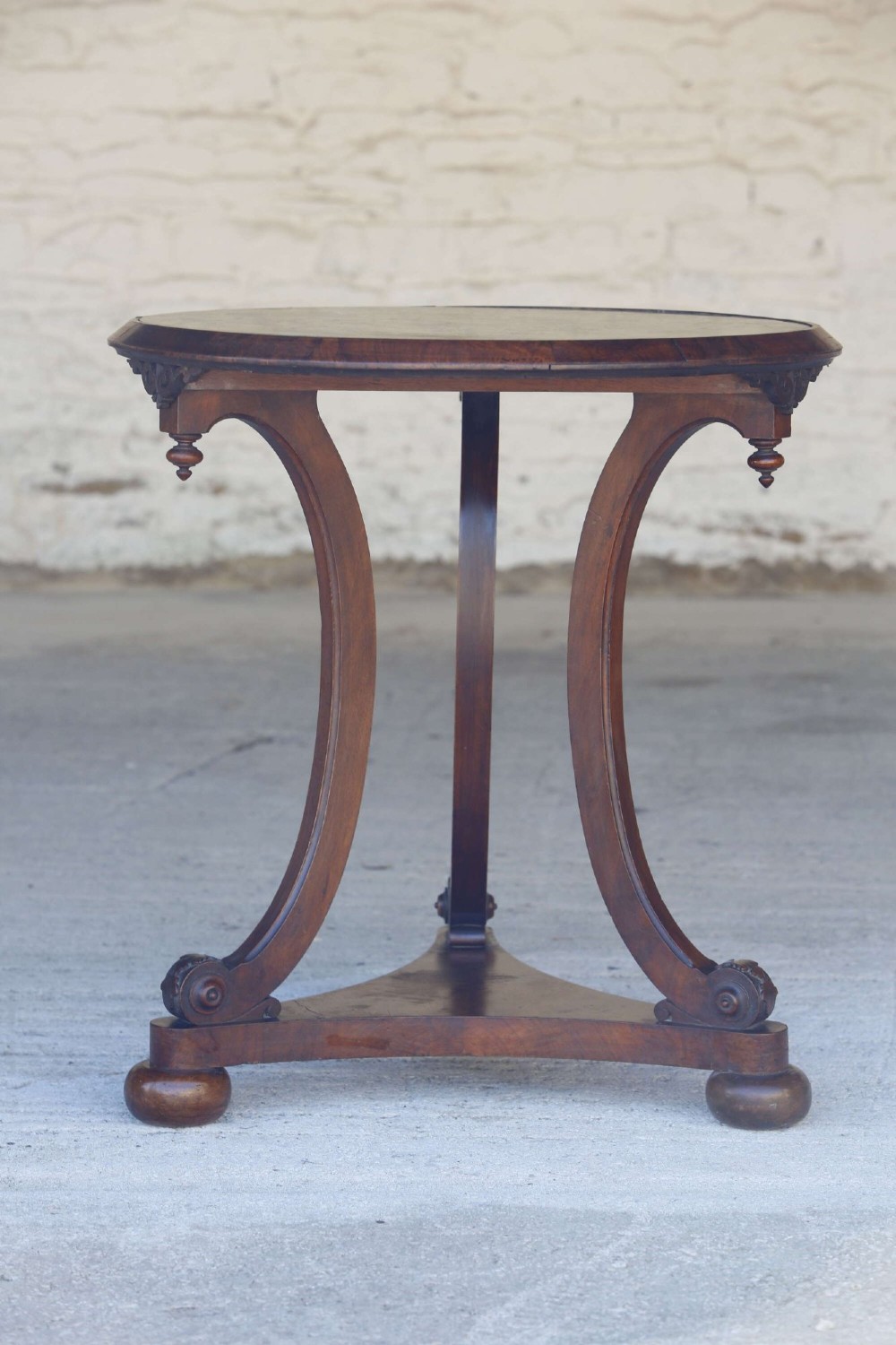 A circular 19th-century French gueridon table featuring a dark green marble top supported by three curved mahogany legs resting on a shaped triform base. View VIII