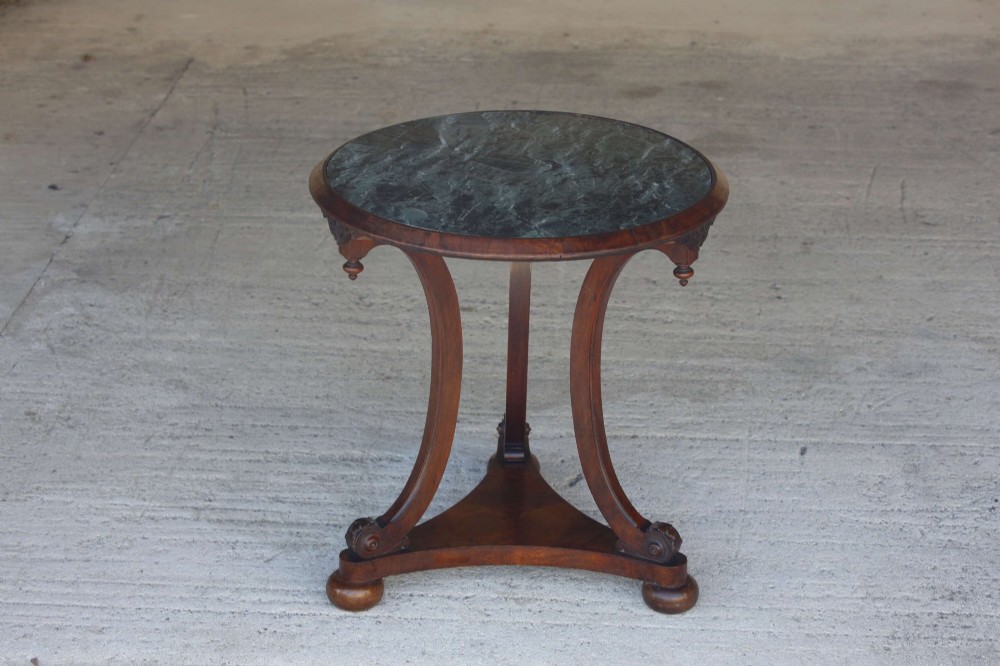 A circular 19th-century French gueridon table featuring a dark green marble top supported by three curved mahogany legs resting on a shaped triform base. View X
