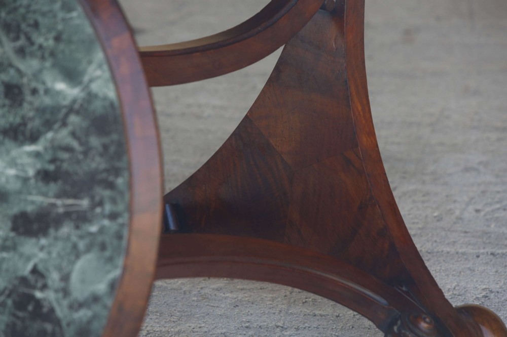 A circular 19th-century French gueridon table featuring a dark green marble top supported by three curved mahogany legs resting on a shaped triform base. View XV