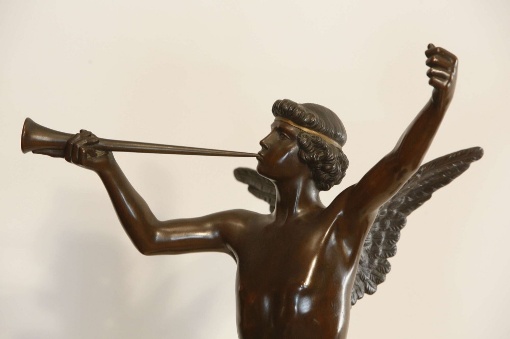 A 19th-century dark brown patinated bronze sculpture depicting the winged Archangel Gabriel blowing a trumpet raised on a round base. View II
