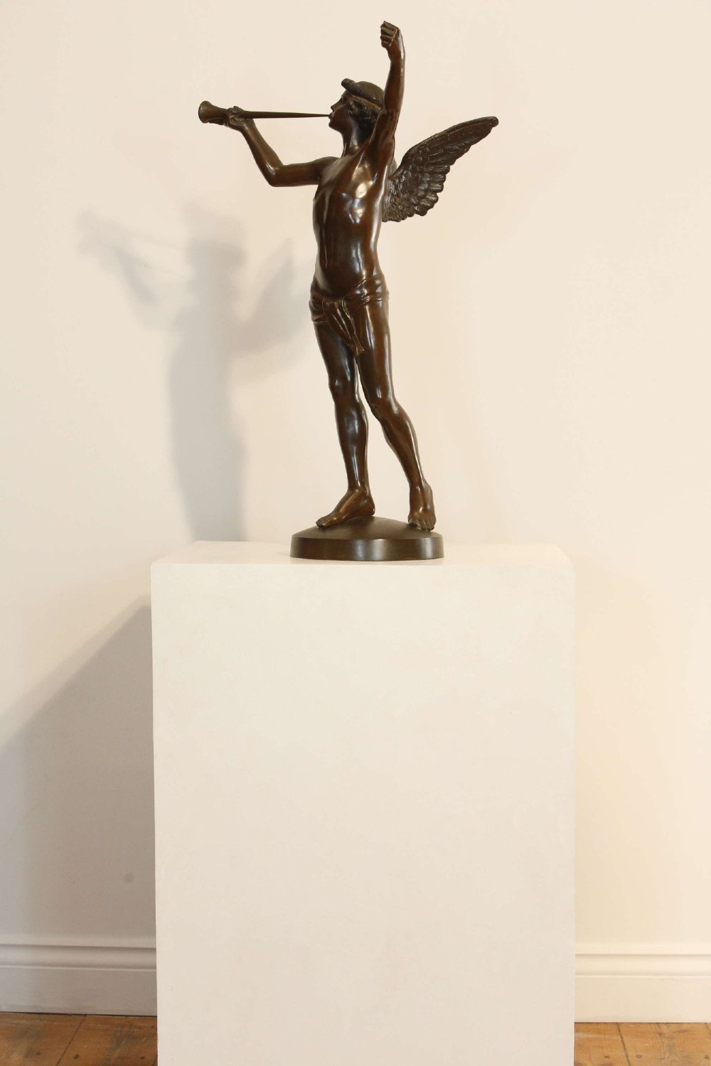 A 19th-century dark brown patinated bronze sculpture depicting the winged Archangel Gabriel blowing a trumpet raised on a round base. View III