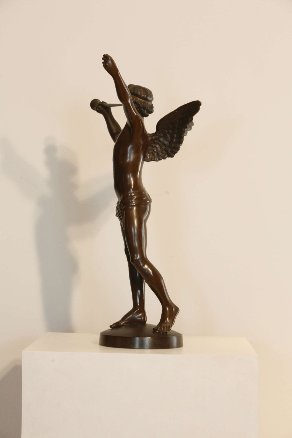 A 19th-century dark brown patinated bronze sculpture depicting the winged Archangel Gabriel blowing a trumpet raised on a round base. View IV