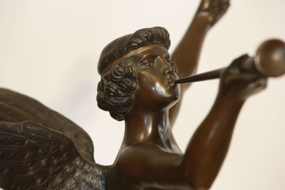 A 19th-century dark brown patinated bronze sculpture depicting the winged Archangel Gabriel blowing a trumpet raised on a round base. View VI
