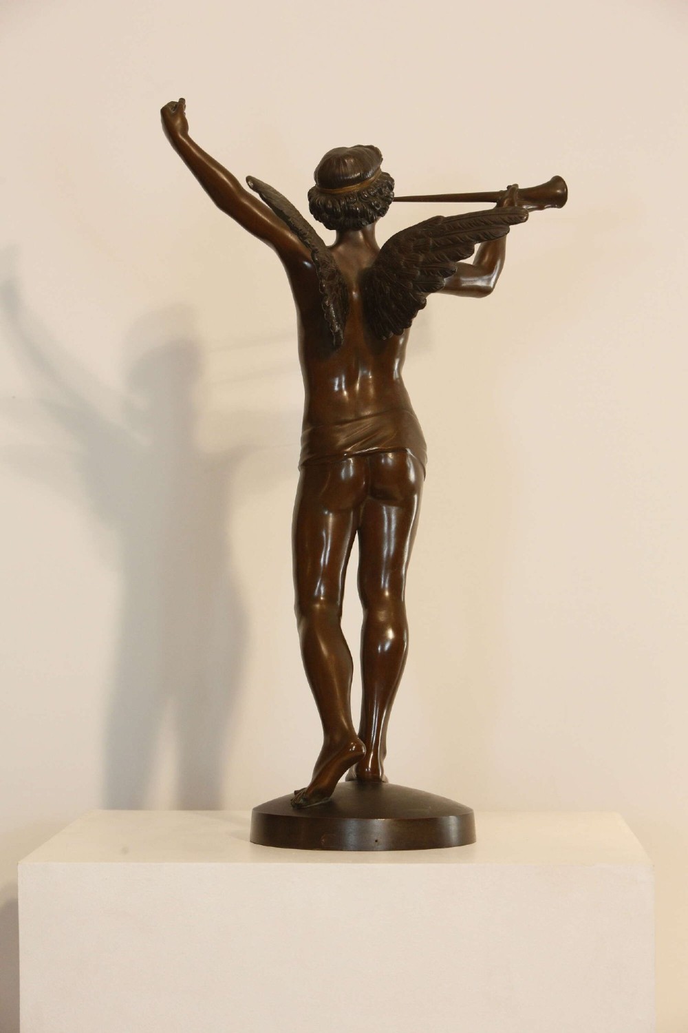 A 19th-century dark brown patinated bronze sculpture depicting the winged Archangel Gabriel blowing a trumpet raised on a round base. View VII
