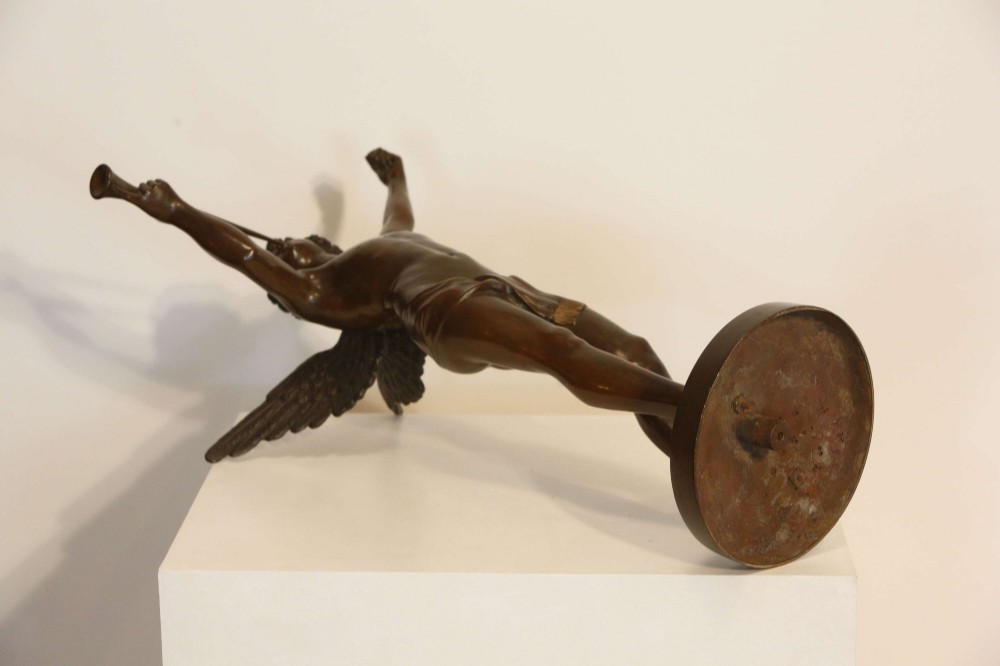 A 19th-century dark brown patinated bronze sculpture depicting the winged Archangel Gabriel blowing a trumpet raised on a round base. View X