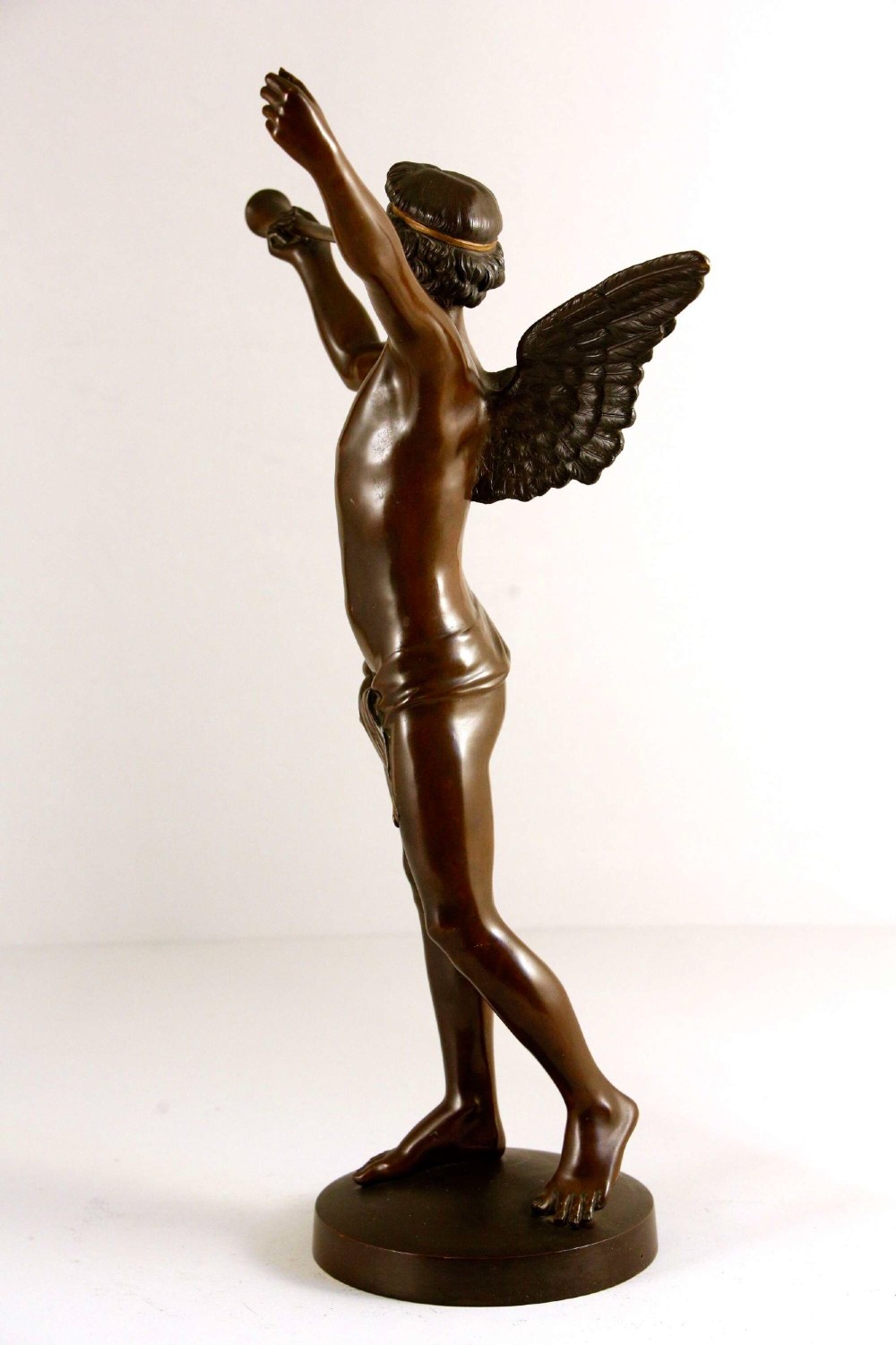 A 19th-century dark brown patinated bronze sculpture depicting the winged Archangel Gabriel blowing a trumpet raised on a round base. View XI