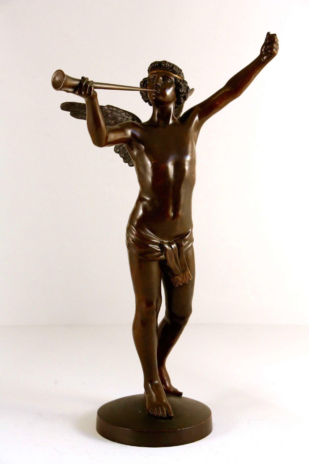A 19th-century dark brown patinated bronze sculpture depicting the winged Archangel Gabriel blowing a trumpet raised on a round base. View XIV