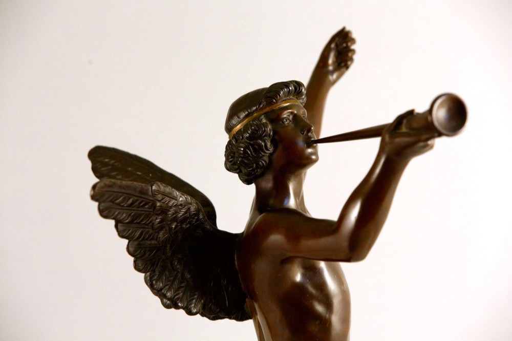 A 19th-century dark brown patinated bronze sculpture depicting the winged Archangel Gabriel blowing a trumpet raised on a round base. View XV