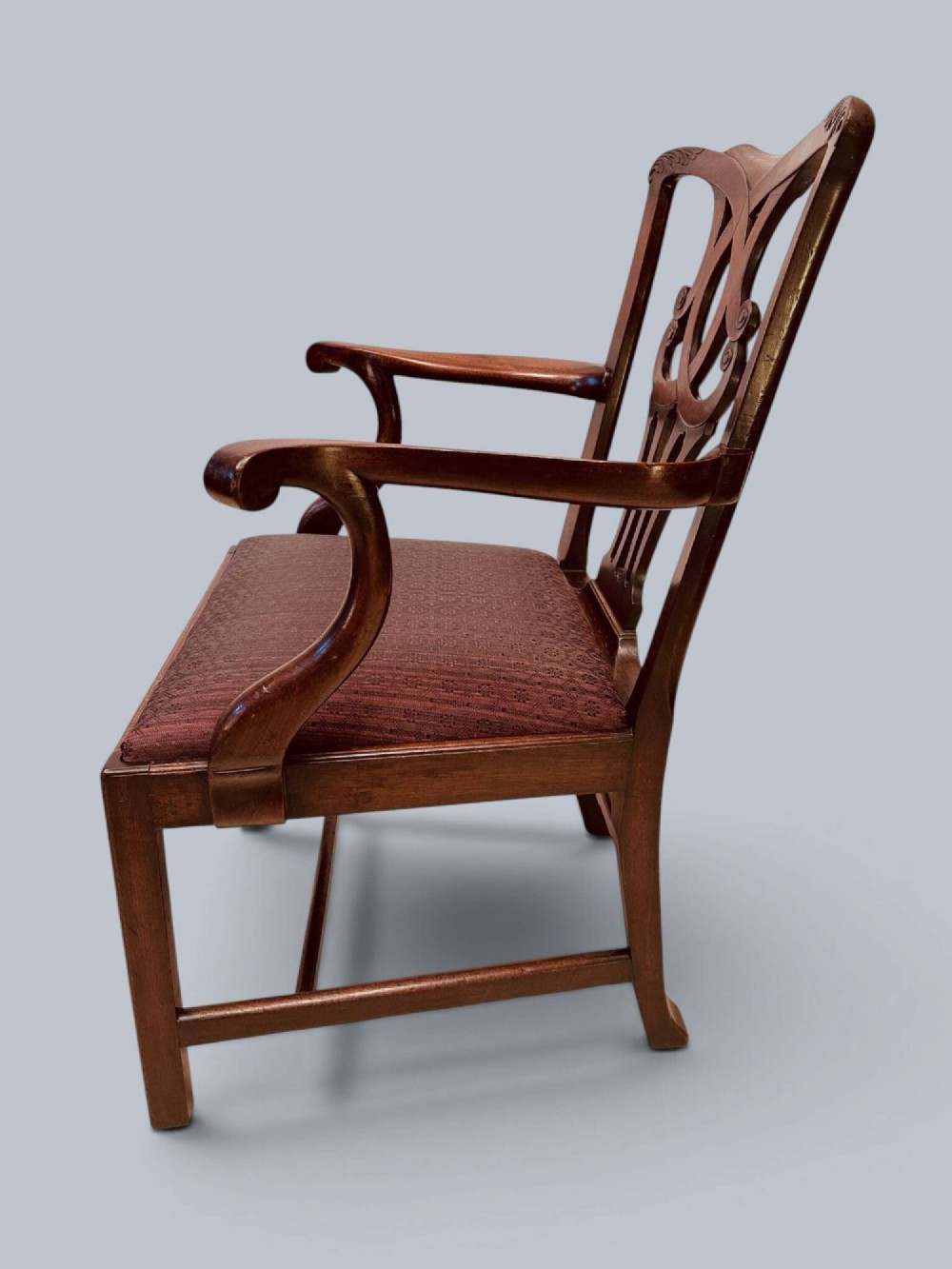 A pair of 19th-century mahogany Chippendale style armchairs featuring carved pierced splat backs, curving armrests, and patterned fabric seats. View V