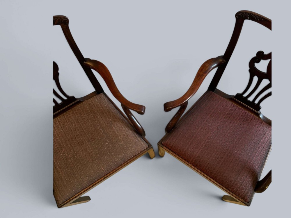A pair of 19th-century mahogany Chippendale style armchairs featuring carved pierced splat backs, curving armrests, and patterned fabric seats. View X