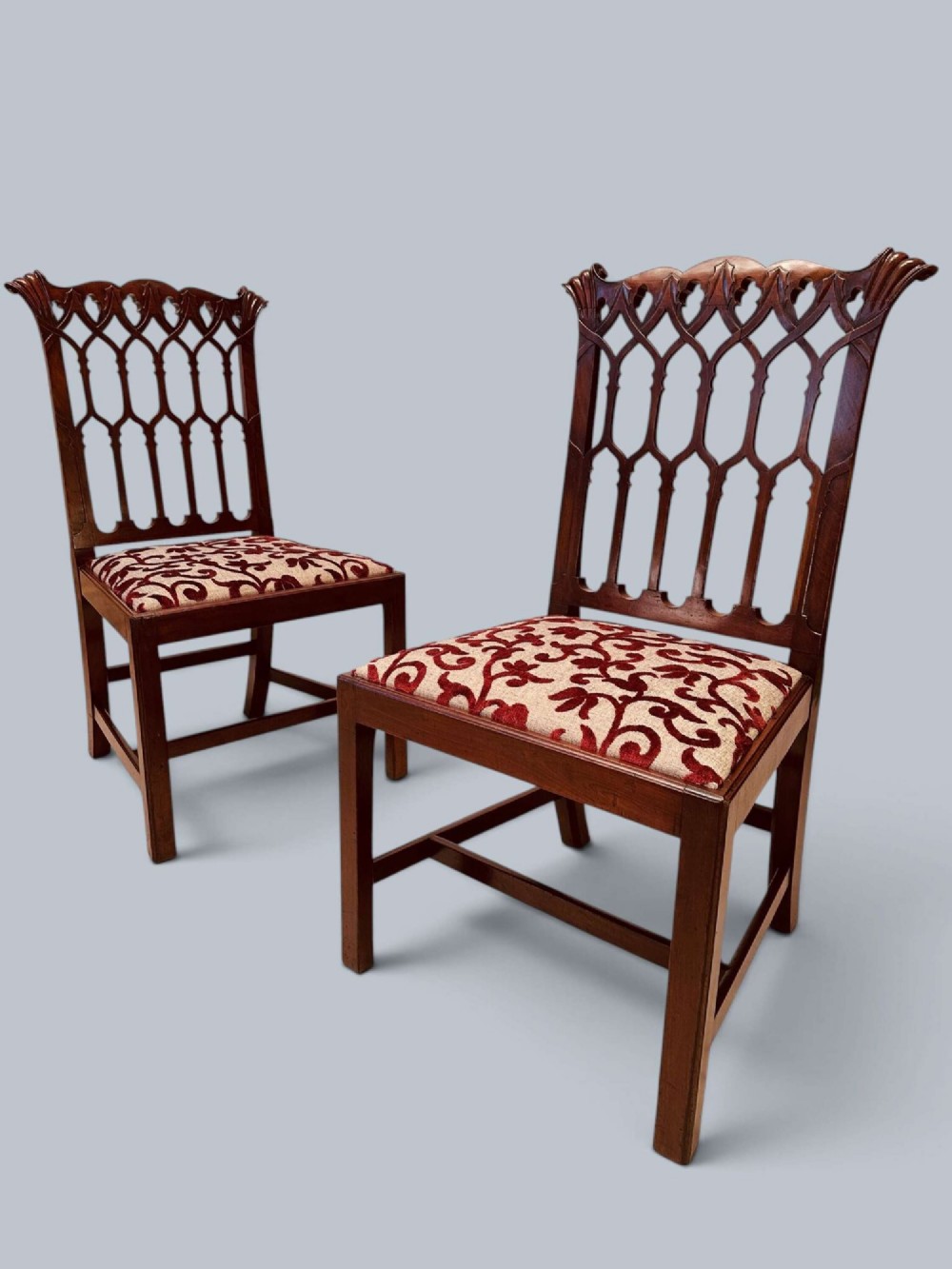 A pair of mahogany side chairs featuring pierced Gothic tracery backrests, straight square legs with H-stretchers, and patterned red fabric upholstery. View III