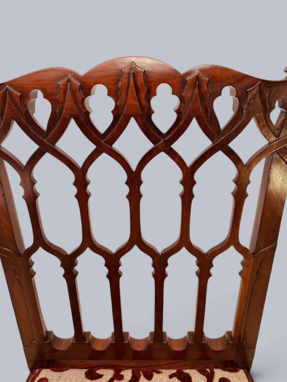 A pair of mahogany side chairs featuring pierced Gothic tracery backrests, straight square legs with H-stretchers, and patterned red fabric upholstery. View IX