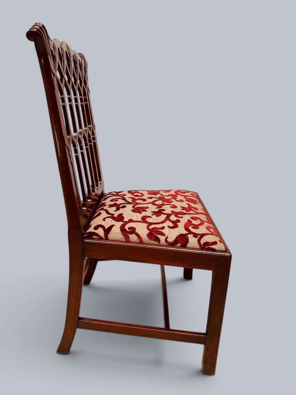 A pair of mahogany side chairs featuring pierced Gothic tracery backrests, straight square legs with H-stretchers, and patterned red fabric upholstery. View XIII