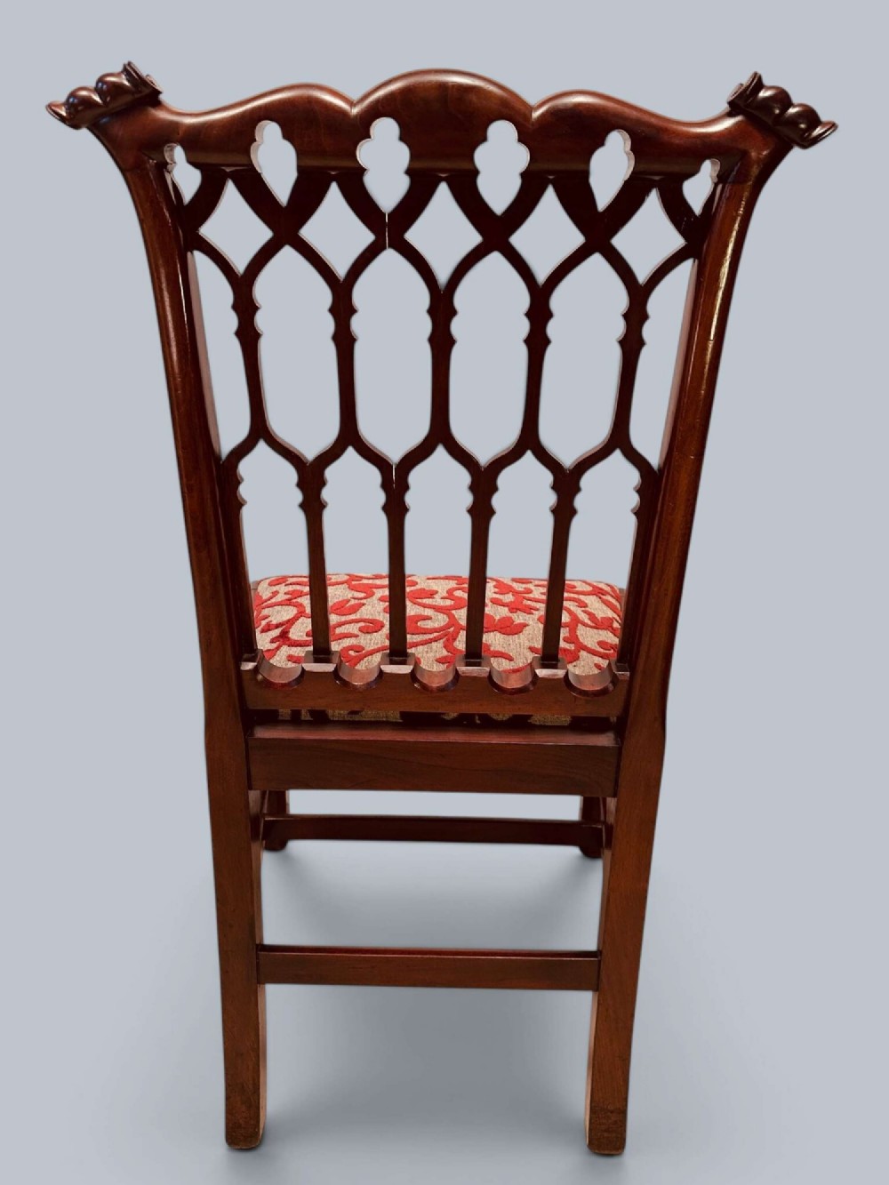 A pair of mahogany side chairs featuring pierced Gothic tracery backrests, straight square legs with H-stretchers, and patterned red fabric upholstery. View XIV