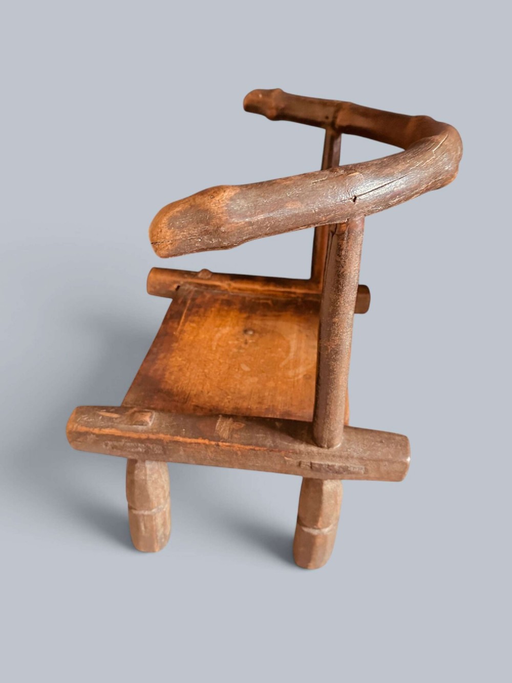 A small hand-carved rustic wooden child chair with a curved branch backrest and chunky square-cut legs. View IV