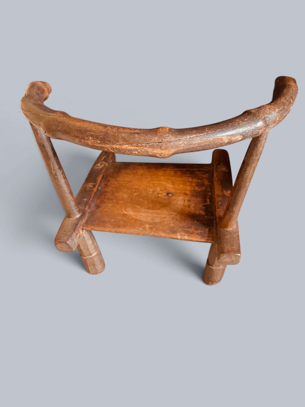 A small hand-carved rustic wooden child chair with a curved branch backrest and chunky square-cut legs. View V