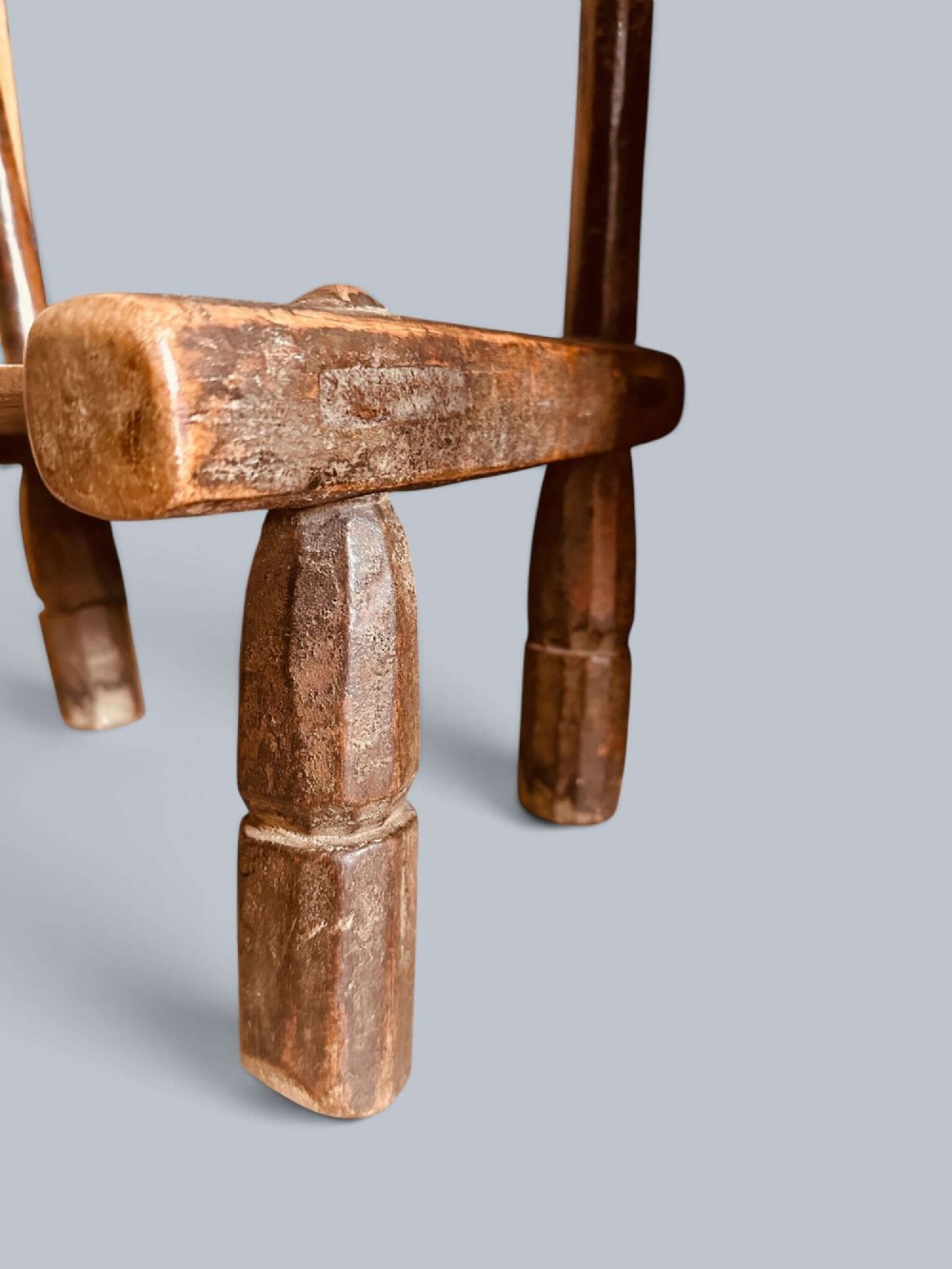 A small hand-carved rustic wooden child chair with a curved branch backrest and chunky square-cut legs. View VI