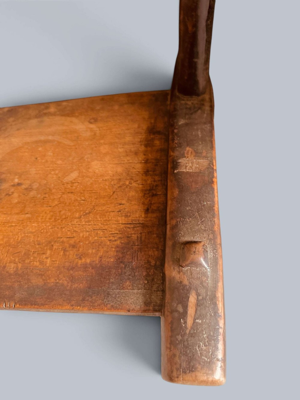 A small hand-carved rustic wooden child chair with a curved branch backrest and chunky square-cut legs. View VII