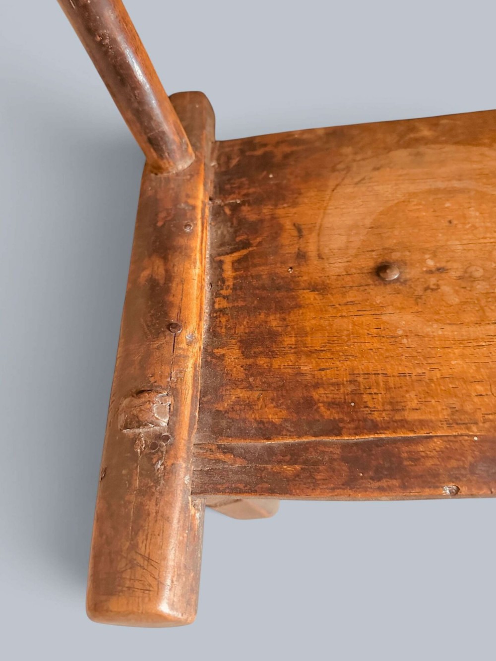 A small hand-carved rustic wooden child chair with a curved branch backrest and chunky square-cut legs. View VIII