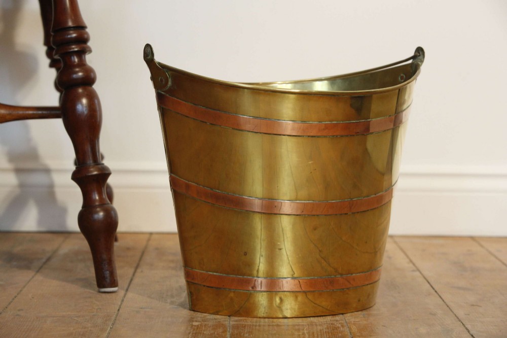 A Georgian brass peat bucket featuring flared sides, three horizontal copper bands, and a curved upper rim. View III