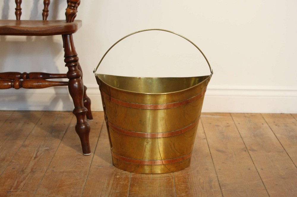 A Georgian brass peat bucket featuring flared sides, three horizontal copper bands, and a curved upper rim. View IV