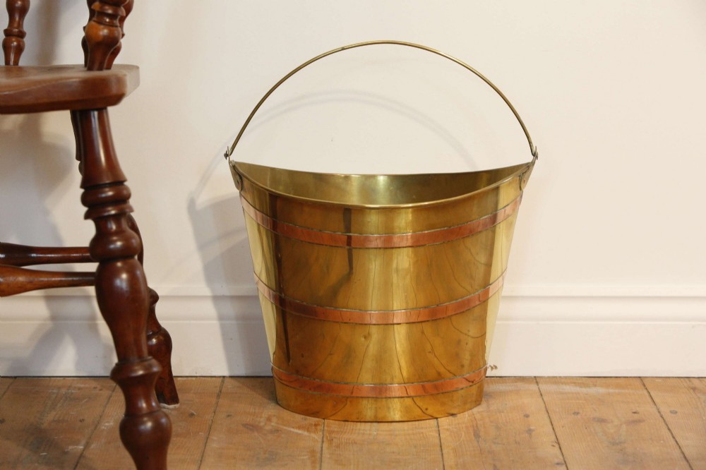 A Georgian brass peat bucket featuring flared sides, three horizontal copper bands, and a curved upper rim. View V