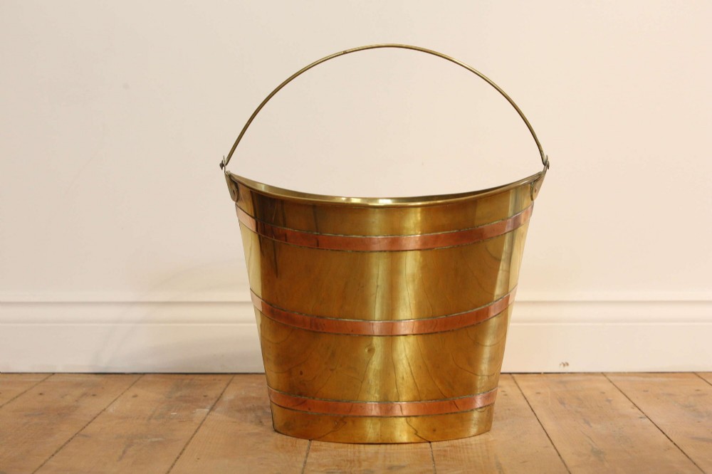 A Georgian brass peat bucket featuring flared sides, three horizontal copper bands, and a curved upper rim. View VI