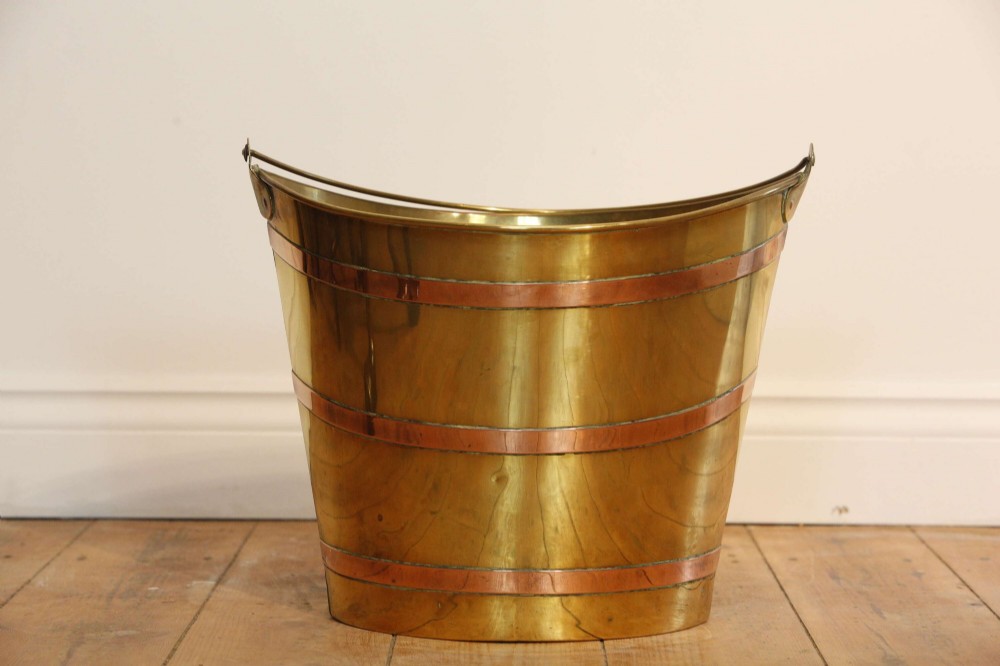 A Georgian brass peat bucket featuring flared sides, three horizontal copper bands, and a curved upper rim. View VII