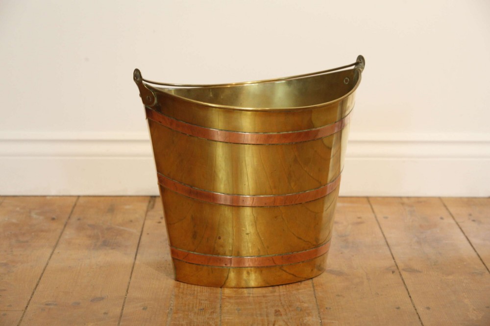 A Georgian brass peat bucket featuring flared sides, three horizontal copper bands, and a curved upper rim. View VIII