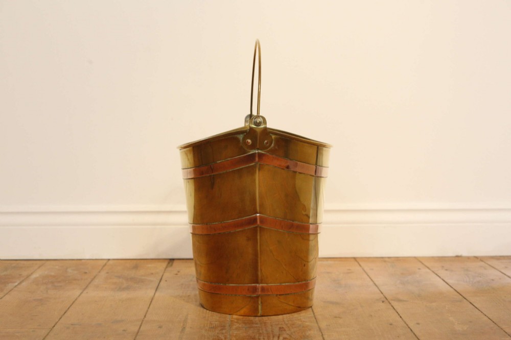 A Georgian brass peat bucket featuring flared sides, three horizontal copper bands, and a curved upper rim. View X