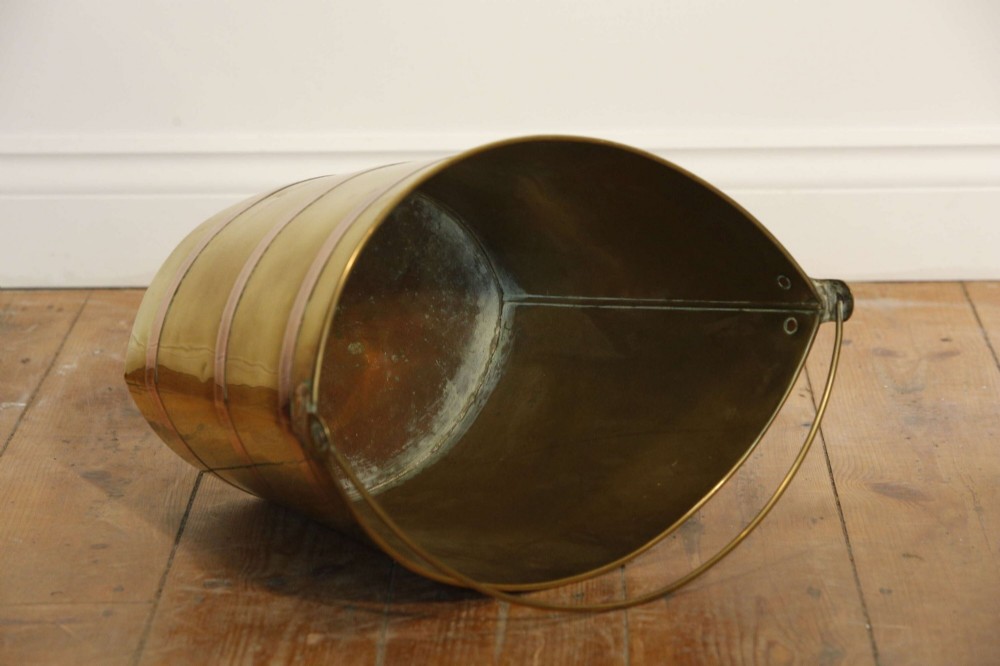 A Georgian brass peat bucket featuring flared sides, three horizontal copper bands, and a curved upper rim. View XI