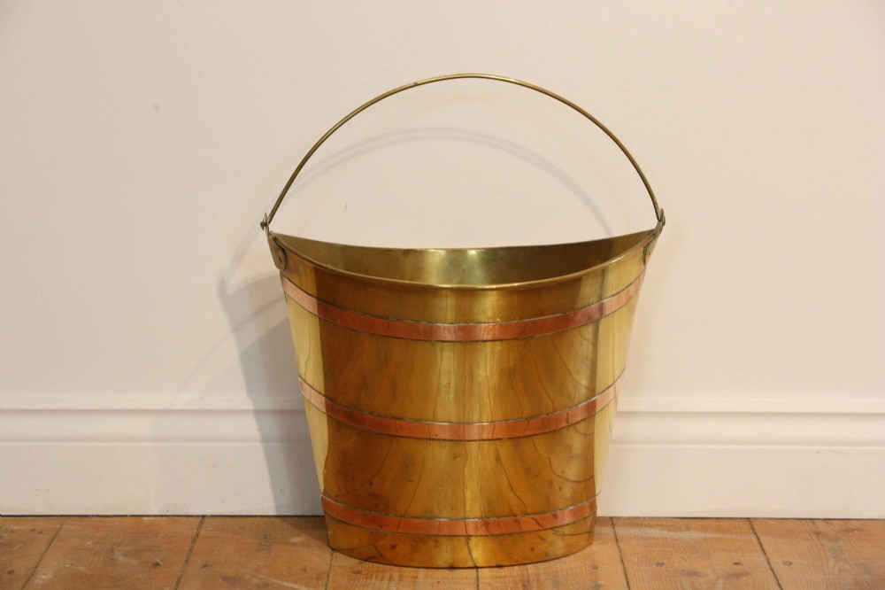 A Georgian brass peat bucket featuring flared sides, three horizontal copper bands, and a curved upper rim. View XII