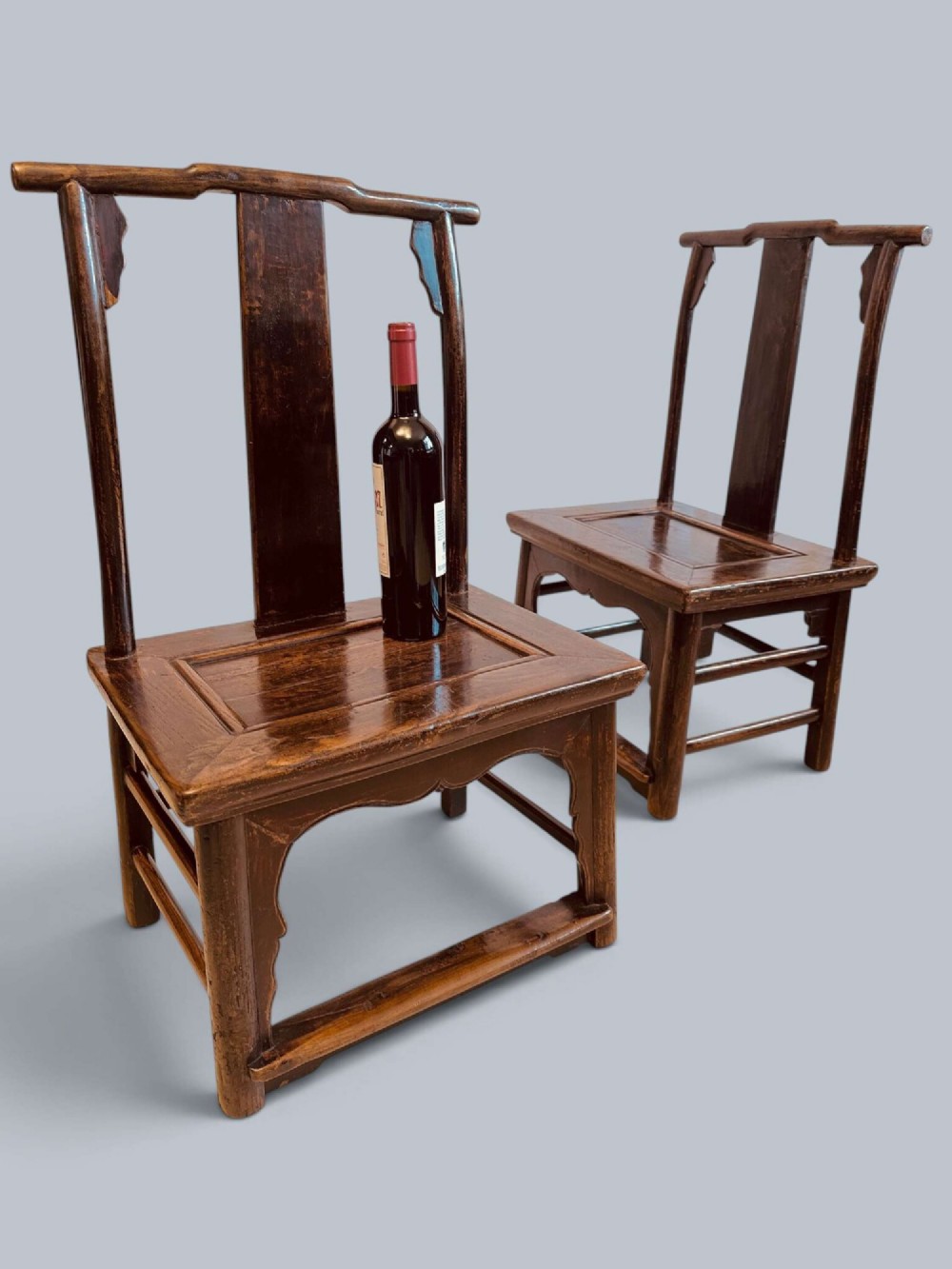 A pair of dark-lacquered antique Chinese childrens chairs with yoke-style top rails and carved aprons. View II