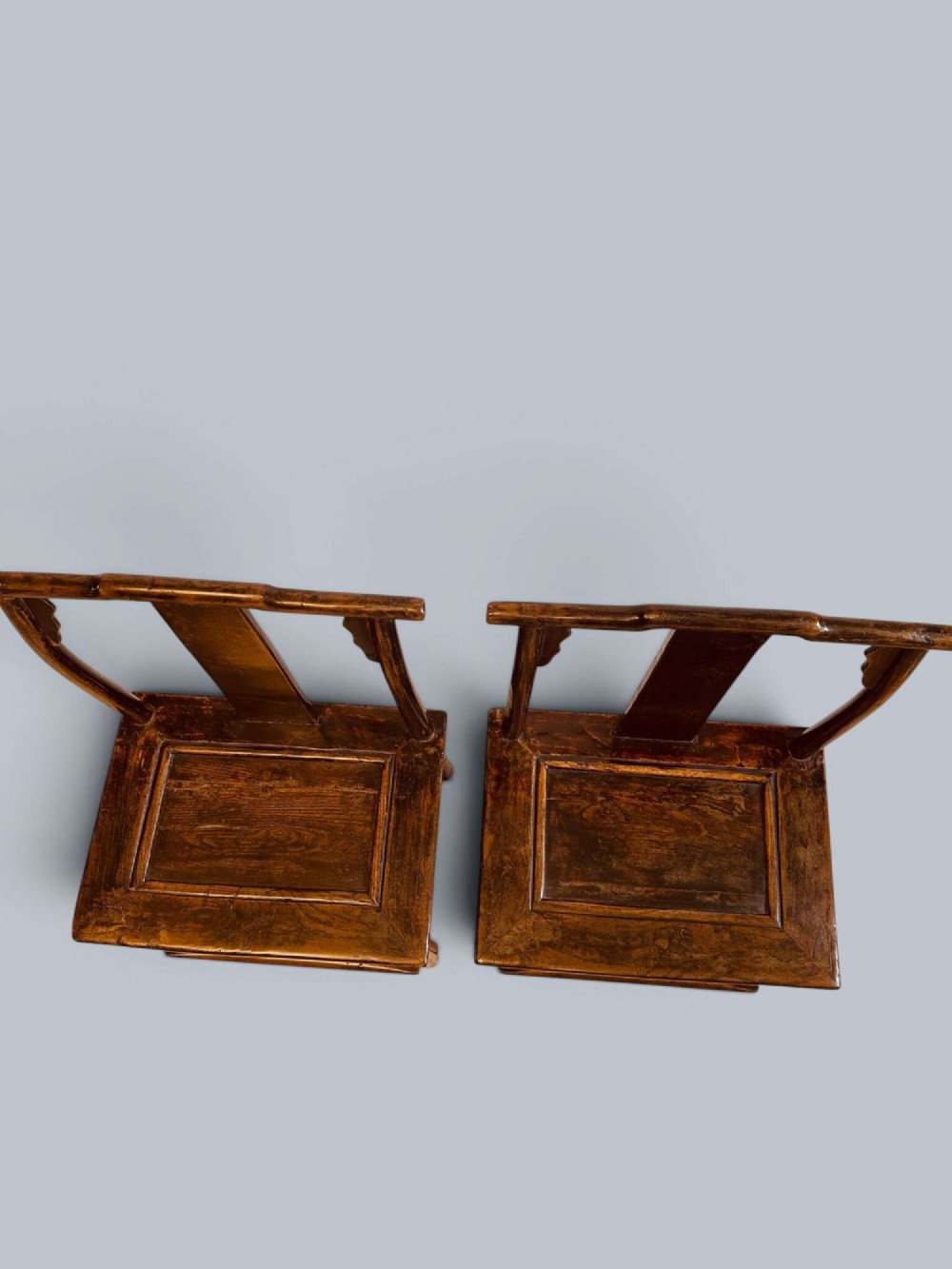 A pair of dark-lacquered antique Chinese childrens chairs with yoke-style top rails and carved aprons. View III